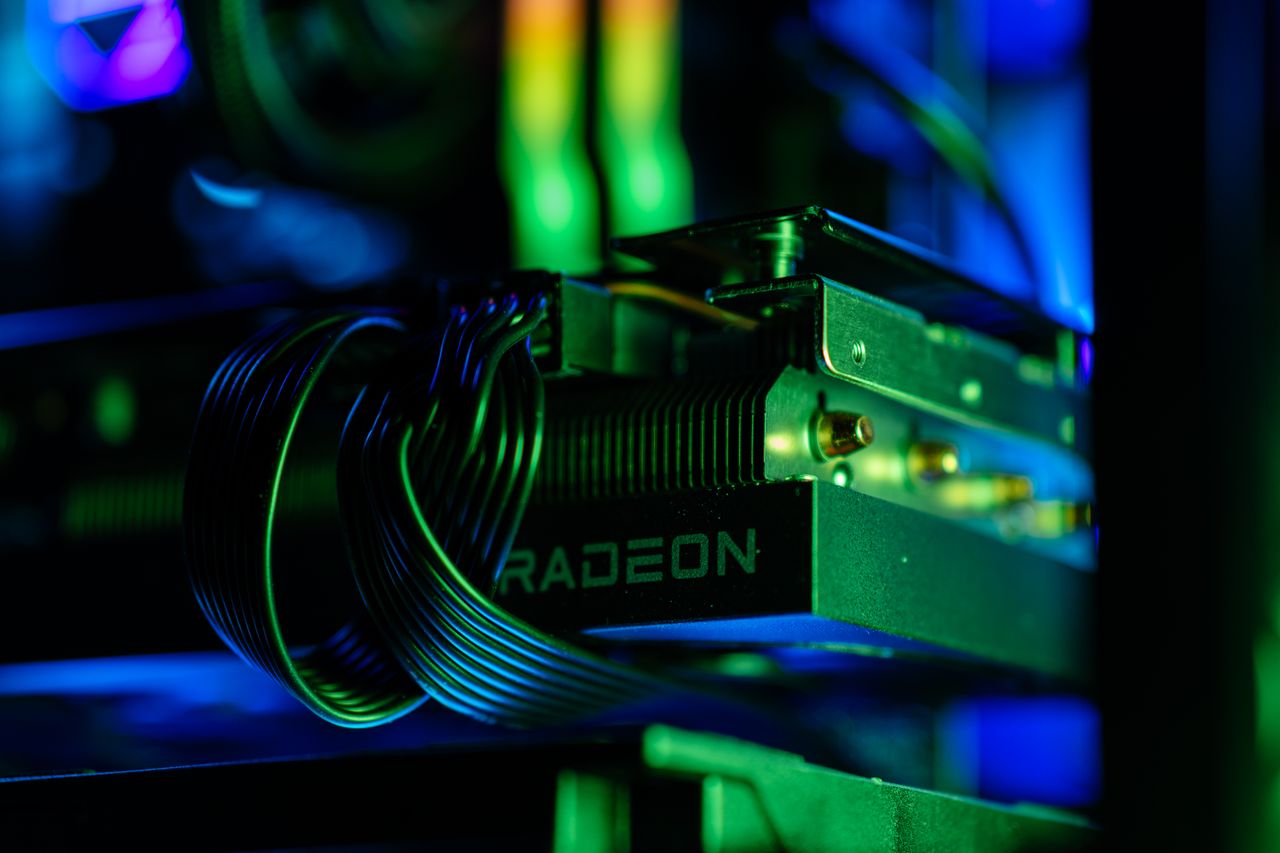 Detailed close-up of a gaming PC's Radeon graphics card with vibrant RGB lighting, showcasing cables and hardware.